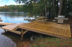 two boats are docked at the end of a wooden dock on a lake surrounded by trees