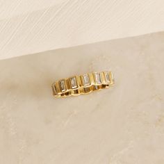 a yellow gold ring with five baguettes on it sitting on a marble surface