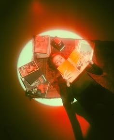 a person laying on the floor reading a book with books around them and an orange light in the background