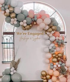 an arch made out of balloons with the words we're engaged on it