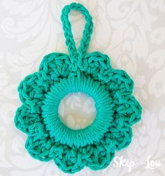 a green crochet doily hanging on a white wall with a circular hole in the center