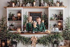 two children are sitting on the mantle with christmas decorations