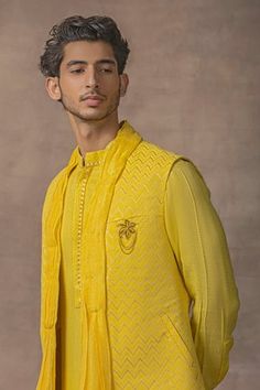 Mustard drape open waist coat with chevron patterns. Comes with kurta and contrast pant.
Components: 3
Type Of Work: Chevon Patterns
Neckline: Kurta: Mandarin
Sleeve Type: Waist Coat: Sleeveless, Kurta: Long
Fabric: Moss Crepe
Color: Yellow
Other Details: 
Kurta:
Cuff sleeves
Concealed placket
Waist Coat:
Draped, attached shawl collar
Pocketed details
Occasion: Wedding - Aza Fashions Sleeveless Kurta, Pattern Draping, Kurta Set For Men, Rohit Bal, Set Saree, Dhoti Pants, Saree Gown, Waist Coat, Chevron Patterns