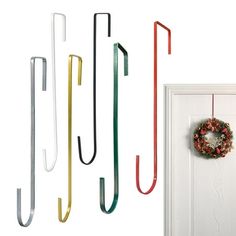 four different colored umbrellas hanging from hooks on a door with a wreath in the middle