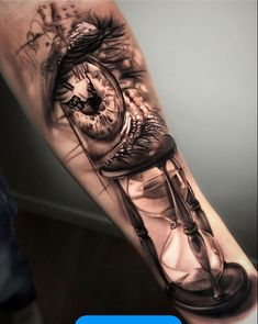 a man's arm with an eye and hourglass tattoo on the left forearm