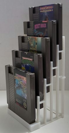 several video games stacked on top of each other in front of a white rack filled with dvd's