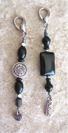 two black and silver beaded charms on a white carpeted surface, one is dangling from a hook