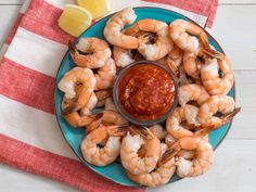 a blue plate topped with shrimp next to a lemon wedge and ketchup sauce