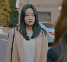 a woman with long black hair walking down the street