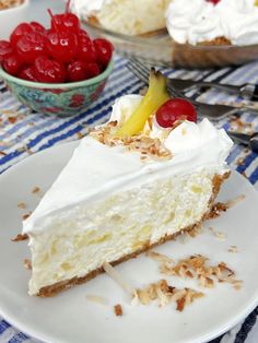 a piece of cheesecake on a plate with cherries in the bowl behind it