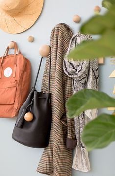 two purses hanging on the wall next to a coat rack with hats and scarves