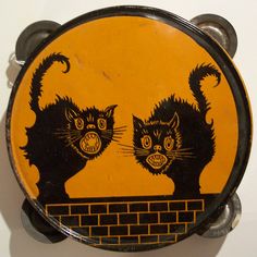 two black cats on yellow and black plate with brick wall in the backround