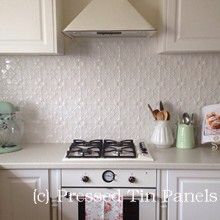 a kitchen with white cabinets and an open cookbook on the stove top, next to a tea kettle