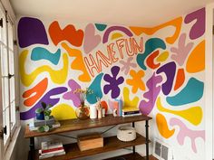 a colorful wall with the word dance fun painted on it in front of a wooden table