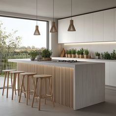 a kitchen with an island and stools next to a window that has plants on it