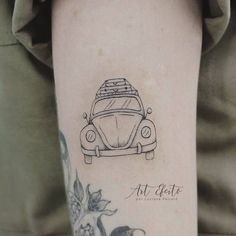 a woman's arm with a small tattoo of a car and flowers on it