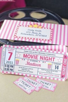 pink and white ticket style movie night birthday party printables on a brown table