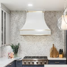 a kitchen with blue cabinets and white counter tops, gold trimming on the hood