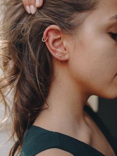 a woman wearing a pair of ear piercings in front of her face and behind her ear