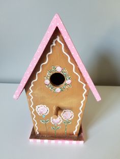 a wooden birdhouse with flowers painted on it's side and a pink roof