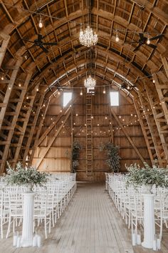 the inside of a barn with rows of chairs and chandeliers