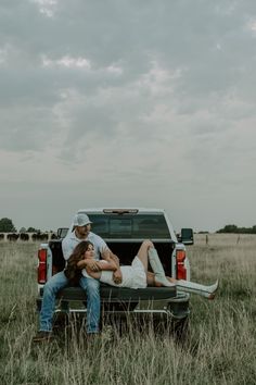 a man and woman sitting in the back of a pick up truck with their arms around each other