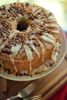 a bundt cake with icing and pecans on top sitting on a plate