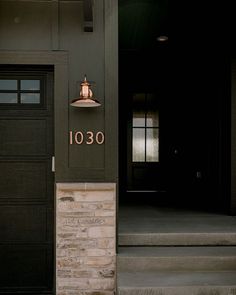 a black door with the number 1030 on it and a light hanging above it