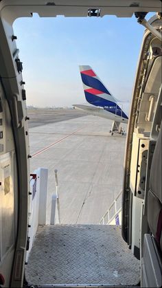 an airplane that is sitting on the tarmac with it's door open and another plane in the background