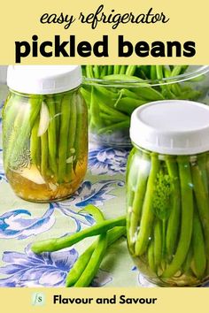 two jars filled with green beans sitting on top of a table