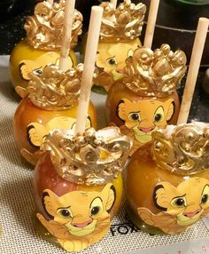 several caramel apples with gold lion faces on them and wooden sticks sticking out of them