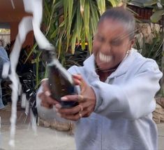 a woman holding a bottle in her hand and spraying it with water from the faucet