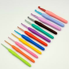 several different colored pens are lined up in a row on a white surface with one black, one pink, one green, and one blue