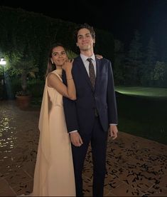 a man in a suit and tie standing next to a woman wearing a cape at night