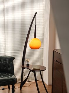 a black leather chair sitting next to a table with a lamp on top of it