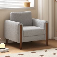 a gray chair sitting in front of a window next to a table with a lamp on it