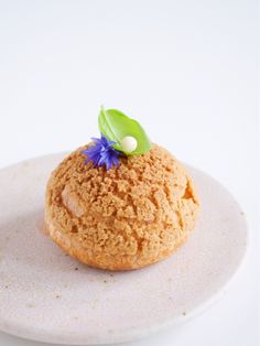 a dessert on a white plate with blue flowers and green leaves sitting on top of it