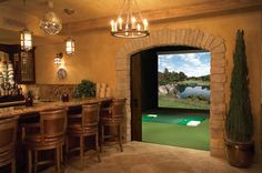 a golf simulator is set up in the middle of a room with bar stools