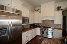 a kitchen with white cabinets and stainless steel appliances