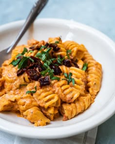 a white plate topped with pasta covered in sauce and garnished with parsley