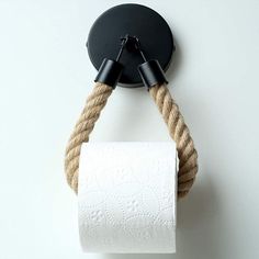 a rope wrapped around a toilet paper dispenser on a white wall with a black hook