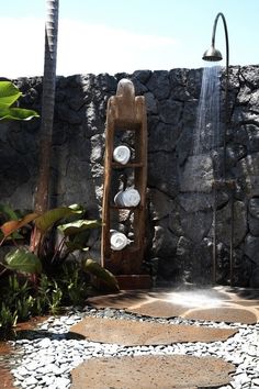 an outdoor shower with water coming out of it's sides and rocks surrounding it