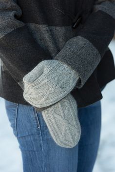 a person wearing mittens standing in the snow with their hands on their hips