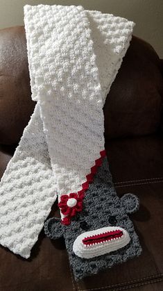 a crocheted sock with a red and white scarf on it