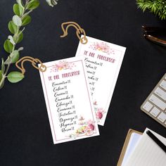 two tags with flowers on them sitting next to a keyboard