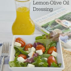 a white bowl filled with salad next to a bottle of lemon olive oil and a glass of orange juice