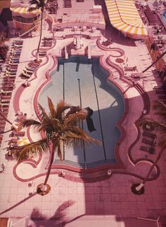 an aerial view of a swimming pool with palm trees and umbrellas in the background