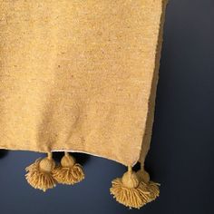 two yellow tassels hanging from the side of a tan blanket on a wall