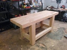 a wooden table sitting in a garage next to other workbench and tools on the floor