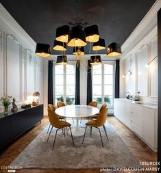 an elegant dining room with black and white walls, wood flooring and yellow chairs